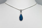 Teardrop-shaped opal pendant on a silver chain against a white background